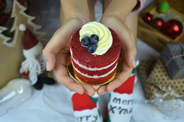 Young woman holding cupcake in hands, with a christmas decorated background close up