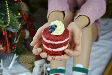 Young woman holding cupcake in hands, with a christmas decorated background close up