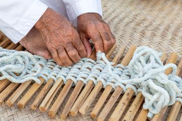 Old man is knitting traditional fishing net, hands in frame