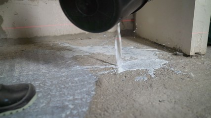 With a special brush, level the primer on the floor. The process of priming concrete floors.