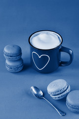 Cup of cappuccino with a heart and Dark classic blue macaroons. Valentines and 8 March Mother Women's Day concept. Small depth of fieldю Color of the year 2020 classic blue toned. copy space 