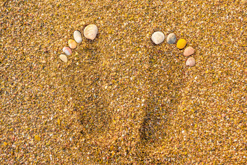 Seashell footprints on the sea coastline. Relieve tension, pain in legs, feet. Massage for feet. Beauty salon. Foot procedures. Spa salon background. View from above. Health of feet and toes