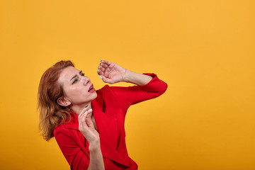Scared caucasian young lady wearing fashion red jacket over isolated orange background dodging a...