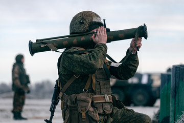 A soldier shoots from a grenade launcher at a military training ground