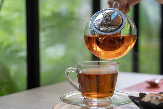 Tea set in clear glass jug and dessert. During leisure time drinking aromatic tea with delicious cookies. Is a relaxed feeling.