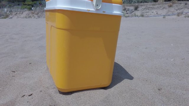 Yellow portable handheld mini fridge the side on sands beach