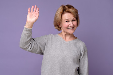 Hello concept. Happy old woman with a smile on her face fallen hand in greeting. Welcoming guests.