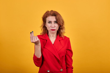 Disappointed caucasian young woman keeping fingers together, looking at camera wearing fashion red...