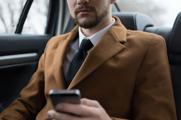 Fototapeta na wymiar portrait of a young guy thirty years old. Businessman in a business style of clothing. Rides in the passenger seat at the office to work, solving problems on the smartphone, talking on the phone