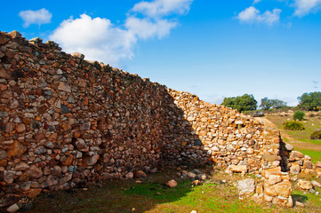 Old stone wall in a green field. Sunny autumn day in Seville, Spain
