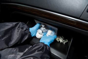 a gloved policeman shows drugs found in a car.