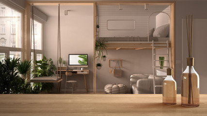 Wooden table top or shelf with aromatic sticks bottles over blurred modern studio apartment with loft bunk bed, mezzanine, swing. Lounge with sofa, white architecture interior design