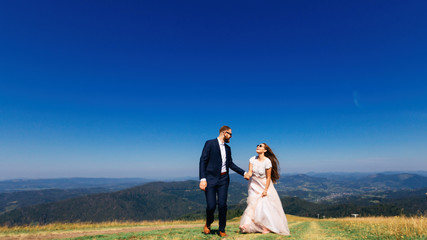 Newlyweds enjoy each other and walk on the top of the mountain w