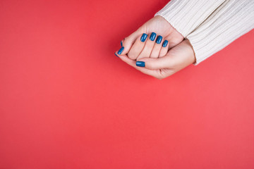 Beautiful women's hands with a neat manicure blue on a red background