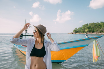 Young woman on a tropical beach near a fishing boat