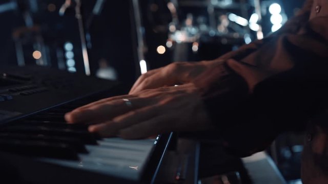 Hands of male musician playing at synthesizer. Mens arms plays solo of music or new melody. Close up fingers of pianist at the piano keys.