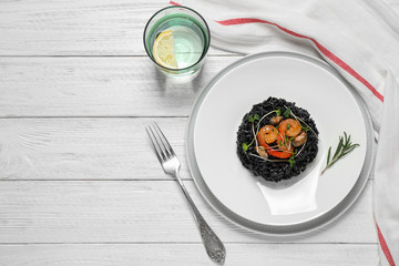 Delicious black risotto with seafood served on white wooden table, flat lay. Space for text