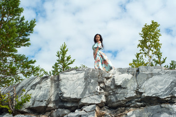 Young woman in long dress posing at marble rock