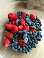 Strawberries, blueberries and honeysuckle in a glass cup