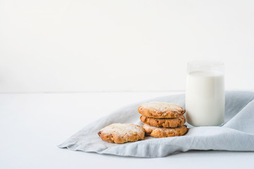 Stacked cookies on a linen napkin and a glass of milk.