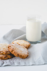 Stacked cookies on a linen napkin and a glass of milk.