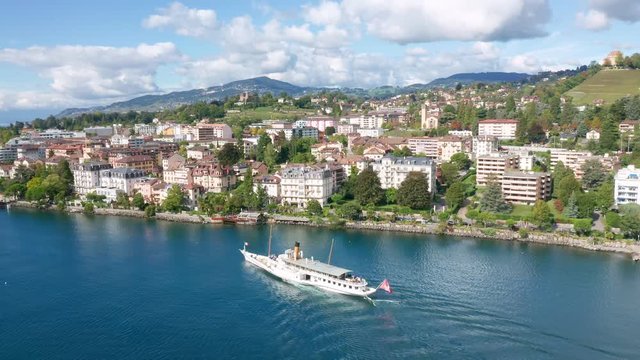 Follow aerial shot of Swiss excursion ship on Lake Geneva. Flag of Switzerland fixed to the stern of boat