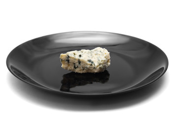 Piece of blue cheese with mold on black plate