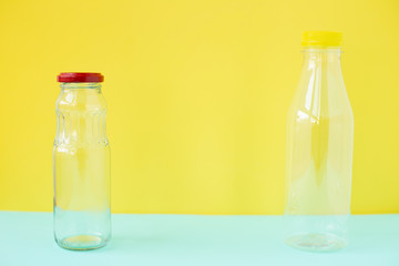 Glass bottle for drinks with a red cap and a plastic bottle on a yellow-blue background. An example of packaging that is healthy and environmentally friendly and then properly recycled and disposed of