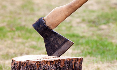 The wood chopper sticks out in wooden hemp. Ax and ax handle. Woodworking. Deforestation by a sharp axe. Ax to chop wood. Rusty but very sharp forester's ax or carpenter's axe.