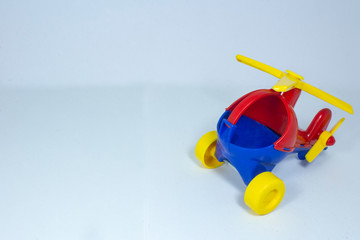 Children's toy, plastic red-blue helicopter with a yellow propeller and wheels on a gray fleecy...