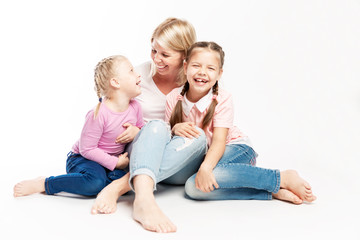 Mom blonde with small daughters hug and laugh. A happy family. White background.