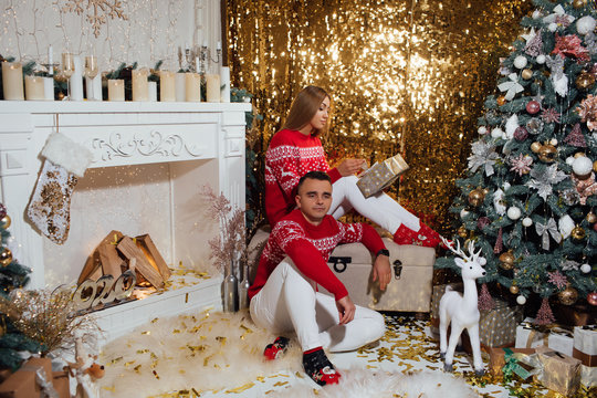 Young beautiful couple celebrate New Year and Christmas. Boyfriend and girlfriend smiling at the camera in cozy elegant christmas sweaters. Christmas decor. The atmosphere of the holidays