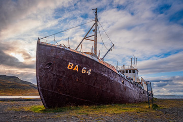 An out-of-the-way whaling ship that rusts on the road to Latrabjarg on a dead cloudy day. The shipwreck has the identification BA 64 and is located on a beach in the west of Iceland