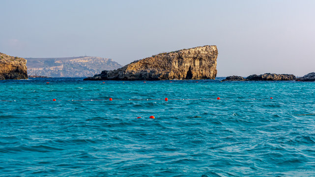 Rock in cyan water of Mediterranean sea in Blue Lagoon, located between Comino and Cominotto islands, Malta.