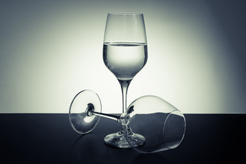 two wineglasses on a table with a colored background
