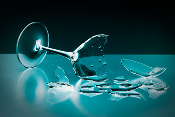 broken wineglass on the table with colored background