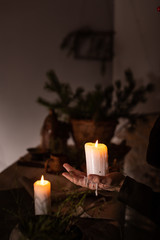 A woman dressed in a medieval dress holds a burning white candle in her hand. Mystery witch
