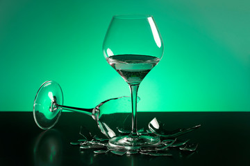two wineglass one of them broken and lies on the table