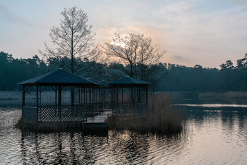 An island with summer pavilions in the lake in the evening. A place to relax on the lake.