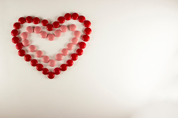 Colorful dragee beans in the shape of a heart on a white background. Decoration background. Closeup.