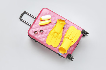 Suitcase with travel accessories on light background