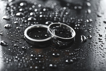 Obraz na płótnie Canvas Pair of wedding rings on wet table
