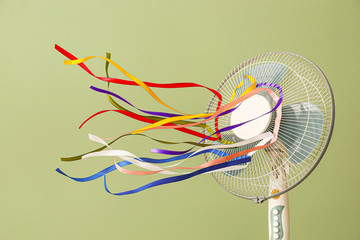Fototapeta Electric fan with fluttering ribbons on color background obraz