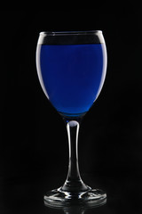 Glass of wine. Blue drink on a black background.