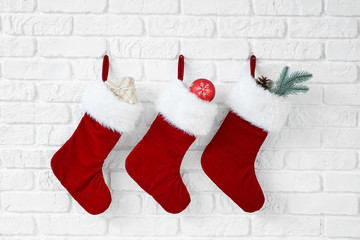 Christmas socks with gifts hanging on white brick wall
