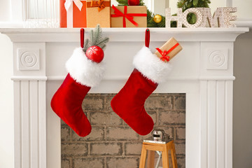Fototapeta premium Christmas socks with gifts hanging on fireplace in room