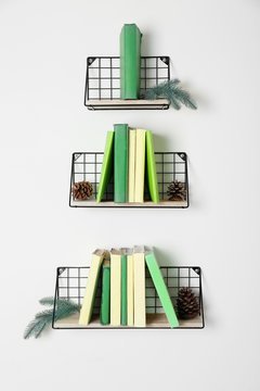 Creative Christmas tree made of shelves with books on light wall