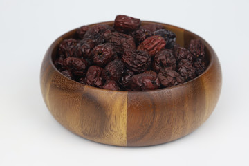Dried Red Jujube Fruit (Dried Red Dates) in wooden bowl on white background