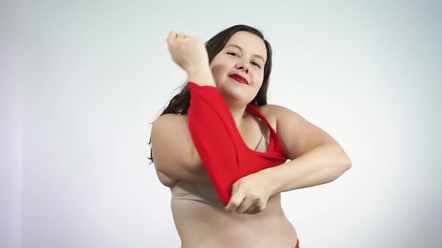 Body positive concept.Plump lady undresses looking at camera and smiling