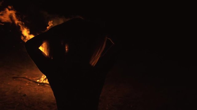 Silhouette of mystic woman in black background of fire fly flame, spark, of contour outline. Adult sexy of young girl witchcraft ceremony ritual dance in underclothes. Outdoor slow motion. Caucasian.